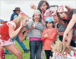  ??  ?? Above: Tallulah, left, and Sierra O’donnell, right, being attacked by Hokitika Zombies at the 2012 Wild Food Festival. Tallulah O’donnell about to bite into a flambe´ed cicada on satay.