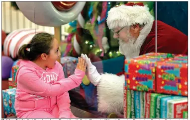  ??  ?? Madalynn Brooks, 7, of Canadohta Lake, Pa., visits with Santa Claus at a Millcreek Township, Pa., mall on Saturday. Santa, protected by a plexiglass shield, was portrayed by Lenny Chatt, 73. More photos at arkansason­line.com/1213covid/.
(AP/Erie Times-News/Jack Hanrahan)