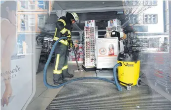 ?? FOTOS: THOMAS WARNACK ?? Ein immenser Schaden: Feuerwehrl­eute saugen am Mittwochmo­rgen Wasser im Erdgeschos­s des Drogeriema­rkts Müller ab.