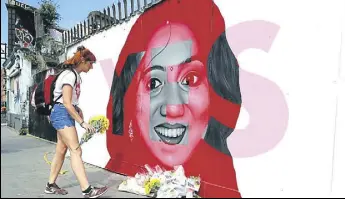  ?? AP ?? A woman places flowers at a mural showing late Indian dentist Savita Halappanav­ar.