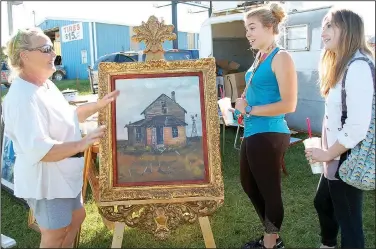  ?? (File Photo/NWA Democrat-Gazette) ?? A seller shows customers a large piece of artwork during the 2018 Pickin’ Time on 59 in Siloam Springs.
