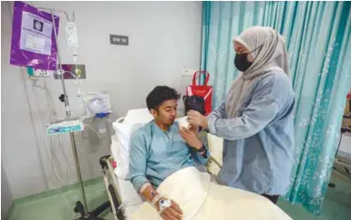  ?? HAFIZ SOHAIMI/THESUN ?? Mohamad Hilmi being tended to by his wife while undergoing treatment. –