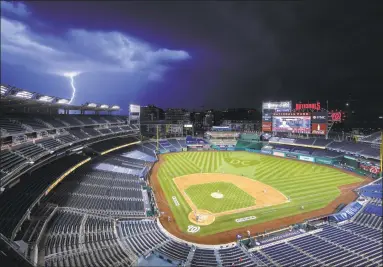  ?? Alex Brandon / Associated Press ?? A bolt of lightning strikes during the sixth inning of an opening day game between the Washington Nationals and the New York Yankees at Nationals Park in Washington on Thursday night.