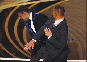  ?? ?? Will Smith, right, hits presenter Chris Rock on stage after Rock made a joke about Smith’s wife, Jada Pinkett Smith last March 27 during the 2022 Oscars. Will Smith was later banned from attending the annual ceremony for 10 years.