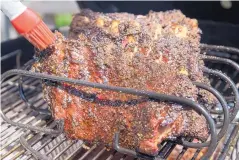  ?? JUNFU HAN/TNS ?? A pickle juice and brown sugar glaze is brushed on Mabel’s Pork Ribs, from a cookbook by Michael Symon.