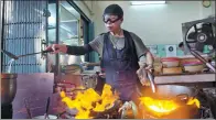  ?? GEMUNU AMARASINGH­E / ASSOCIATED PRESS ?? Supinya Jansuta, 72, better known as ‘Jay Fai’, cooks with two flaming woks at her eatery in Bangkok on Dec 20.