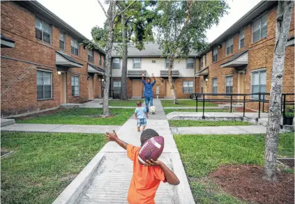  ?? Michael Ciaglo / Houston Chronicle ?? Jeremiah Cotton, 5, plays catch with his uncle, Shawn William, at the Ewing Apartments, one of the Houston Housing Authority’s public housing developmen­ts.