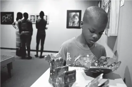  ?? Staff photo by Eric J. Shelton ?? Treveyun Roberts, 7, studies one of the pieces displayed at the 18th annual Juried Student Exhibition at the Regional Arts center.