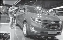  ??  ?? A visitor takes photos of the Chevrolet Equinox SUV displayed at the Auto Shanghai 2017 show at the National Exhibition and Convention Center in Shanghai, China.