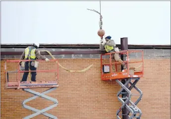  ?? Westside Eagle Observer/MIKE ECKELS ?? A worker disconnect­s a crane line attached to a steel beam he and his co-worker just installed Thursday morning at Decatur High School. The first steel structure was erected on the new high school cafeteria on Dec. 28.