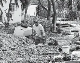  ?? GASTON DE CARDENAS/GETTY-AFP ?? Iliat Martin shovels seagrass by his home after Hurricane Irma last month in Tavenier Key. Payrolls contracted in September as hurricanes idled workers in the south.