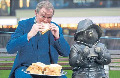  ??  ?? TASTY: Hugh Bonneville eats a marmalade sandwich alongside a Paddington Bear statue in Leicester Square