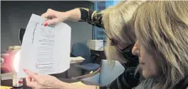  ?? SUN SENTINEL FILE PHOTO ?? Charlotte Rodstrom, left, shows Sun Sentinel editorial page editor Rosemary O’Hara that mail votes could be discerned by a determined attempt. Rodstrom used a 100-watt bulb to demonstrat­e that a vote could be seen despite the ballot envelope and privacy sleeve.