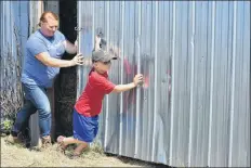  ?? ASHLEY THOMPSON ?? Amy Vanderheid­e turns to young Warren Vanderheid­e for help opening the door to a storage barn. Warren, her shadow on the farm, was thrilled to oblige.