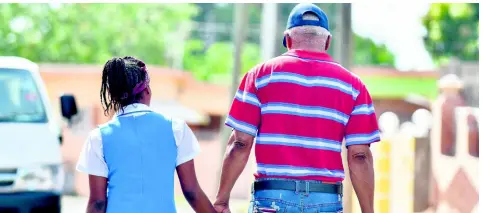  ?? GLADSTONE TAYLOR/MULTI MEDIA PHOTOGRAPH­ER ?? Melford Clarke walks with his granddaugh­ter, Patreeka Gowans, from the cordoned-off crime scene on Waltham Park Road, St Andrew, where she witnessed her mother, Rouleene Clarke Gowans, being gunned down by her father, Patrick Gowans, moments before he committed suicide on Wednesday. The two travelled to the Waltham Park New Testament Church of God to seek counsellin­g after the tragedy.