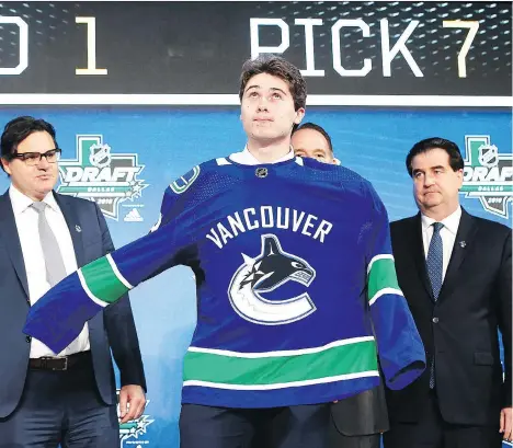  ?? THE ASSOCIATED PRESS ?? Quinn Hughes dons a Canucks jersey after the Canucks selected him with the No. 7 pick in the NHL draft on Friday.