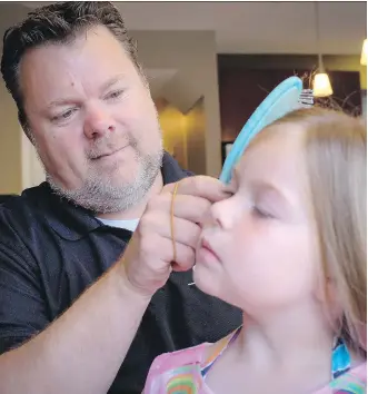  ?? JEFF McINTOSH/ THE CANADIAN PRESS ?? Scott Dry brushes his daughter Reese’s hair at their home in Chestermer­e. Dry was one of 15 fathers who recently took part in a father-daughter hair workshop.