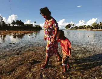  ?? Tribune News Service file photo ?? Josephine Noka walks with her son Jules, 6, along the island of Ejit in the Marshall Islands last year. The nation has a travel ban in place to prevent the introducti­on of the coronaviru­s.