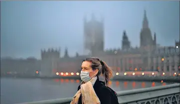  ??  ?? A commuter walks across Westminste­r Bridge with the Houses of Parliament in the background on a foggy morning in London.