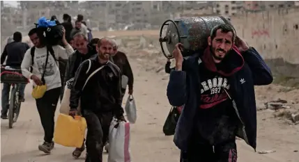  ?? ?? WHERE TO NEXT?
Displaced Palestinia­ns carry their belongings on a street in the city of Khan Younis, southern Gaza Strip on Wednesday, March 6, 2024.