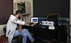  ??  ?? Syrian rapper Amir al-Muarri works on his computer in his room.