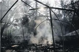  ??  ?? Smoke smoulders from a wildfire-ravaged home on Saturday in Sonoma, California.