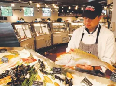  ??  ?? Pete Marczyk of Marczyk Fine Foods holds a whole fish for sale at the fish counter.