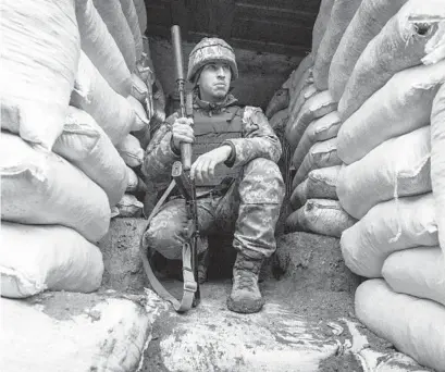  ?? ANDRIY DUBCHAK/AP ?? A Ukrainian soldier sits in the trench on the line of separation from pro-Russian rebels in the Mariupol, Donetsk region, Ukraine, last week. Washington and its allies have promised consequenc­es against Russia — though not military action — if it invades.