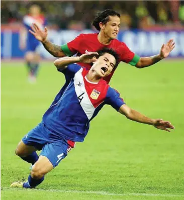  ??  ?? Hard fall: Laos’ Ketsada Souksavanh is pushed by Indonesia’s Irfan Bachdim during the AFF Suzuki Cup Group B match at the National Stadium in Bukit Jalil last night. The match ended 2-2.