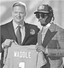  ?? DAVID DERMER/AP ?? Alabama wide receiver Jaylen Waddle, right, holds a team jersey with NFL Commission­er Roger Goodell after he was chosen with sixth pick by the Dolphins in the first round of the NFL football draft.