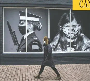  ?? PETER J THOMPSON/NATIONAL POST ?? A pedestrian wearing a mask walks past photos by photograph­ers Dave Chan, left, and Jennifer Long at a Toronto exhibit called Portraits In Covid Times: Documentin­g A Nation In Change.