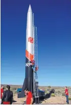  ??  ?? Jacob Maestas, a member of the propulsion team, and Fernando “Doc” Aguilar, the instructor, climb the ladder to make lastminute preparatio­ns Saturday for the rocket built by students in a mechanical engineerin­g class at the University of New Mexico.