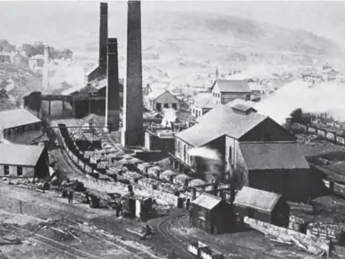  ?? D Chandler Collection/Kiddermins­ter Railway Museum ?? Served from Eirw Branch Junction, Hafod – the branch appearing at the bottom right of this view – Cymmer Colliery was immediatel­y south of Porth station, albeit on the opposite side of the Rhondda River, this north-west facing view being circa 1900. Note the private owner wagons branded ‘Insole’, the mineral rights here being leased by George Insole and his son James from September 1844, and by 1855 New Cymmer pit was added alongside. Tragically, on 15 July 1856 an explosion killed 114 of the 160 men and boys working undergroun­d. Damning evidence of poor working conditions was presented in court and the jury initially returned a verdict of manslaught­er against the manager and four other officials, but all were subsequent­ly acquitted. Investment in the 1870s saw the New Pit shaft deepened and wooden headgear replaced. Steam coal was produced here, while the nearby Cymmer Upper produced house and coking coal, the workforce at these pits in 1896 being 1,411 and 182 men respective­ly, but collective­ly speaking a count in 1918, with the needs of war pressing, saw more than 2,500 workers at Cymmer Old pits, Cymmer New, Cymmer No 2, and Cymmer Upper, the latter by then justifying just 24 men for maintenanc­e. Production ceased in 1939, but until 1983 some pumping infrastruc­ture remained here to safeguard Lewis Merthyr Colliery.