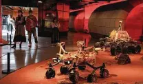  ?? Ng Han Guan / Associated Press ?? Visitors pass by a Beijing exhibition depicting Mars rovers. China said Saturday that its lander had touched down.