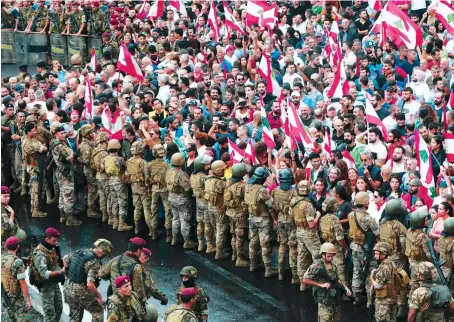  ?? AFP ?? Anti-government protesters facing Lebanese army soldiers wave national flags in the area of Jal Al-Dib in the northern outskirts of on Wednesday.