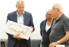  ?? Foto: Heike Scherer ?? Der frühere Präsident des Komitees von Ambérieu Yves Pinon (rechts) überreicht Merings Bürgermeis­ter Hans-Dieter Kandler (links) dieses 7,5 kg schwere Werk aus Marmor von Bruno Charvet (Mitte). Es soll die unzerbrech­lich gewordene Verbindung beider Gemeinden darstellen.