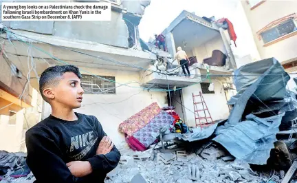  ?? ?? A young boy looks on as Palestinia­ns check the damage following Israeli bombardmen­t on Khan Yunis in the southern Gaza Strip on December 8. (AFP)