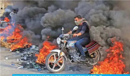  ??  ?? An Iraqi man drives through burning tyres in the Shiite shrine city of Karbala, south of the capital Baghdad, on Nov 26, 2019. — AFP