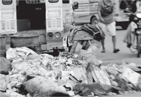  ?? Joey Nacalaban ?? IN CAGAYAN DE ORO. This person looks into garbage bins and trash bags in this busy street to hunt for items that can still be sold to junk shops and recyclable centers.