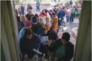  ?? AP PHOTO/EMILIO MORENATTI ?? People queue Tuesday to receive a daily ration of bread in a school in Mykolaiv. the only food distributi­on point in Varvarivka, a Mykolaiv district where thousands of people live.