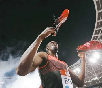 ?? Adrian Dennis/Getty Images ?? Usain Bolt offers his spikes to a fan after winning the 200-meter dash in the IAAF Diamond League Anniversar­y Games Friday in London.