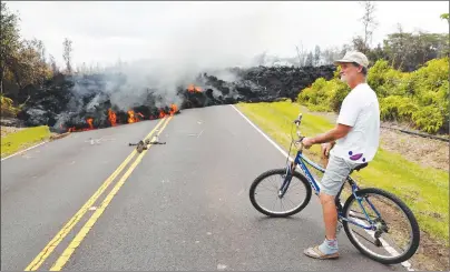  ?? AP PHOTO ?? Leilani Estates resident Sam Knox watches the lava stretch across the road, Saturday in Pahoa, Hawaii. Knox’s home is less than a few hundred yards from the lava flow and he does not have any plans to evacuate.