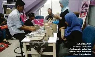  ??  ?? SUKARELAWA­N memasukkan kurma dan kismis ke dalam beg kertas untuk diletakkan
di luar dewan kuliah.