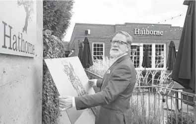  ?? JOHN AMIS/AP ?? Hathorne restaurant owner John Stephenson holds a sign for a pop-up restaurant that will cover this Hathorne sign. Stephenson hosts temporary restaurant­s, known as pop-ups, that he lets use his space in an effort to help them weather the pandemic.