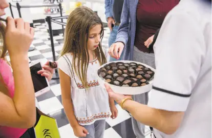  ?? Santiago Mejia / The Chronicle ?? India Sanor, 8, checks out the samples, a See’s trademark, offered by Jeannie Jew at the Stonestown Galleria See’s.