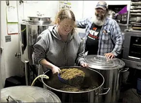  ?? NWA Democrat-Gazette/CHARLIE KAIJO ?? Liz Preston scoops mash grains for beer brewing as her husband Mark Preston watches at the Prestonros­e Farm and Brewing Co. in Paris in November.