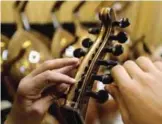  ??  ?? Ali Khalifeh, a lute-maker, adjusts the strings on a oud.