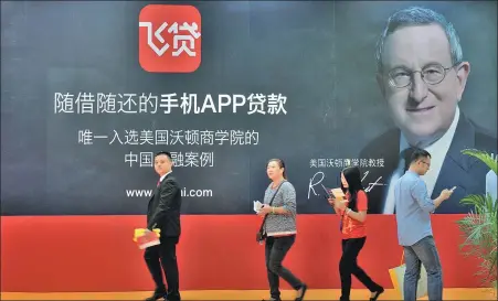  ?? PROVIDED TO CHINA DAILY ?? Visitors walk past a signage for a mobile loan app at a financial exhibition in Shenzhen, Guangdong province.