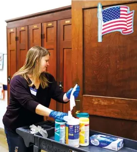  ?? STAFF PHOTO BY DOUG STRICKLAND ?? Parent volunteer Erin Rosener wipes down door handles and other surfaces Tuesday during a group effort to sanitize surfaces at Chattanoog­a School for the Arts and Sciences.