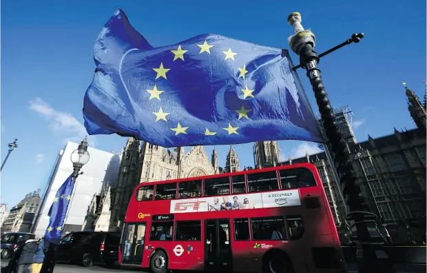  ?? DANIEL LEAL- OLIVAS / AFP / GETTY IMAGES ?? A double- decker London bus drives past an EU flag outside of the Houses of Parliament on Friday. Brexit and NAFTA talks have been fraught with divisivene­ss and obstacles rather than progress, exacerbati­ng global uncertaint­y and leaving policymake­rs...